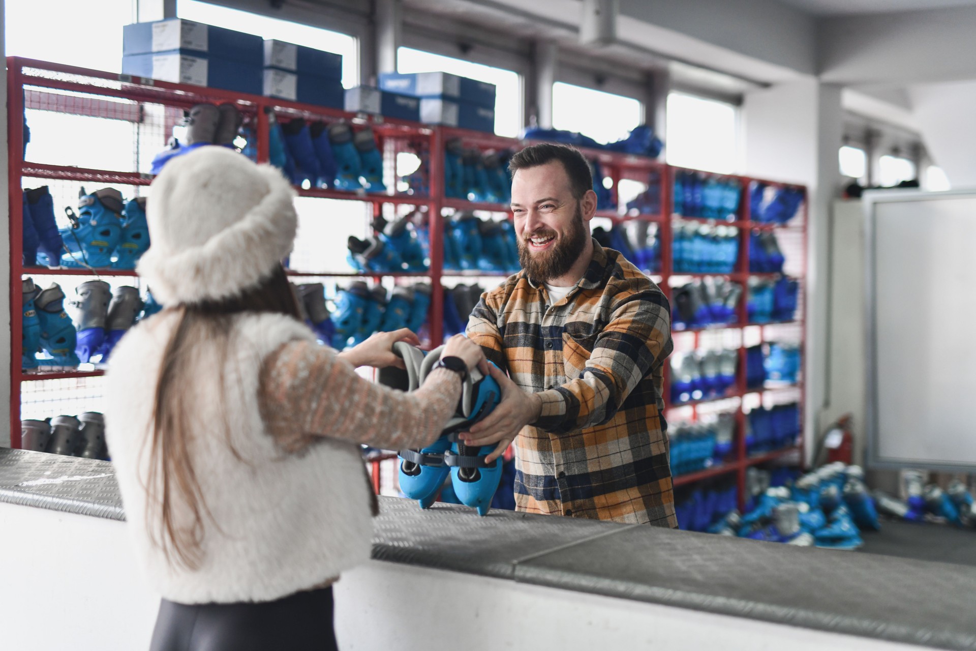 Friendly Male Working at Ice Skating Rink Handing Female Figure Skates